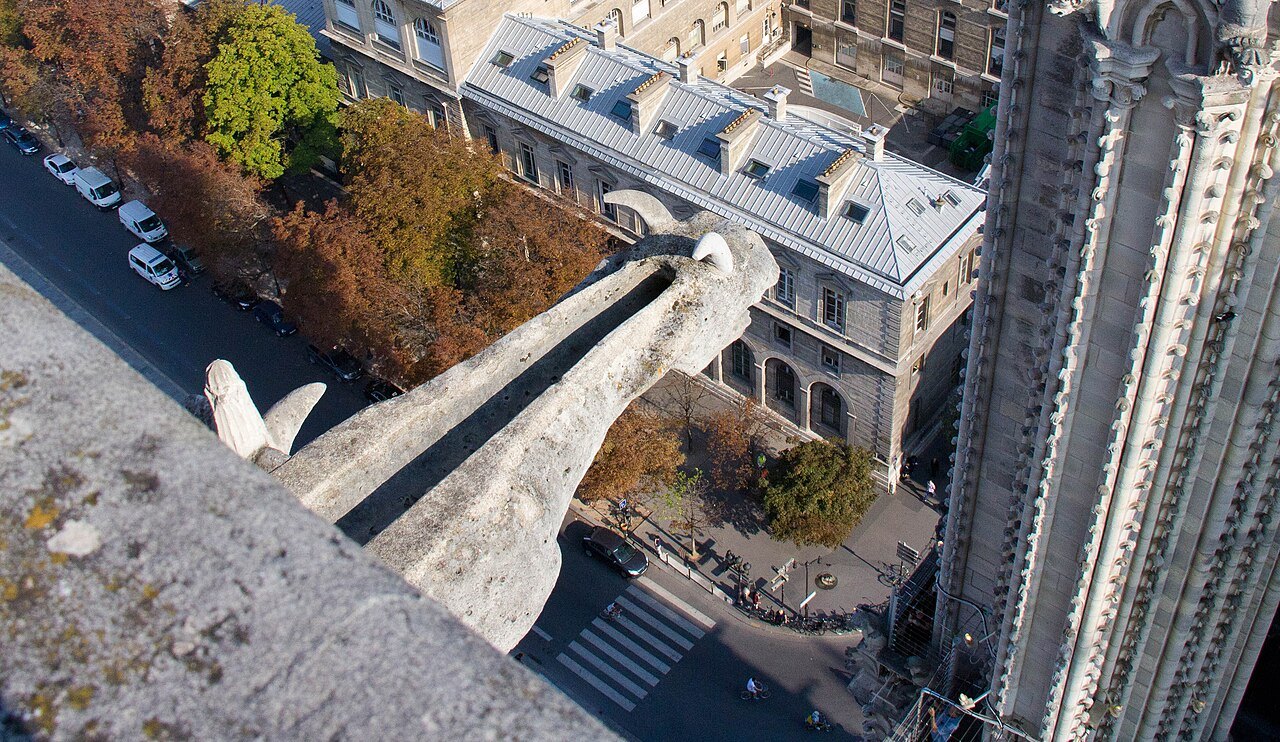 A gargoyle jutting from Notre-Dame high above the street