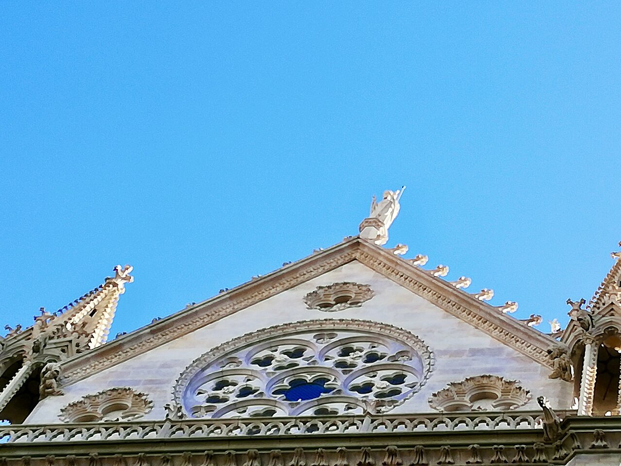 The south transept gable of Notre-Dame and its rose window against a blue sky