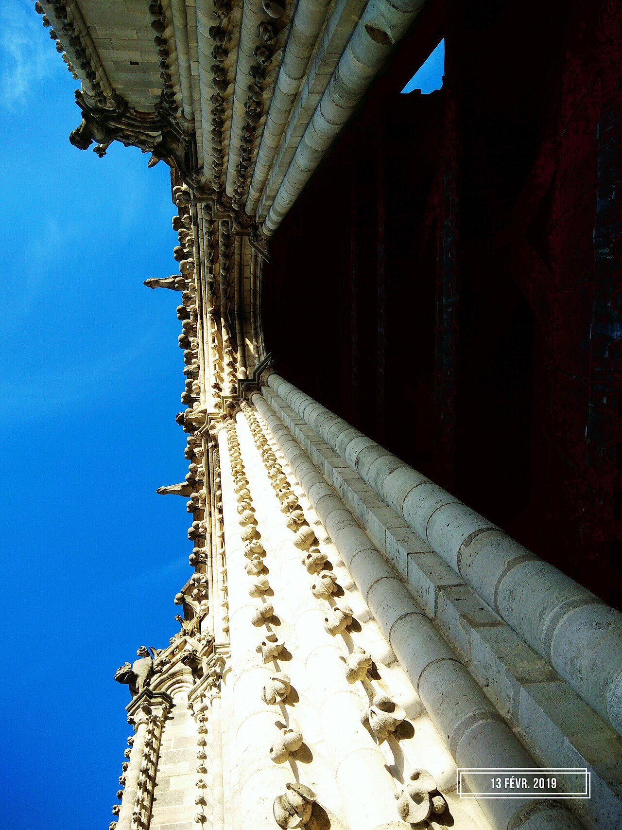 Looking straight up the stonework of Notre-Dame's north tower into a blue sky
